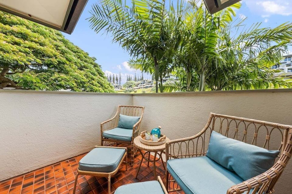 Private lanai with rattan seating and tropical greenery, perfect for enjoying morning coffee or evening cocktails in a serene outdoor setting.