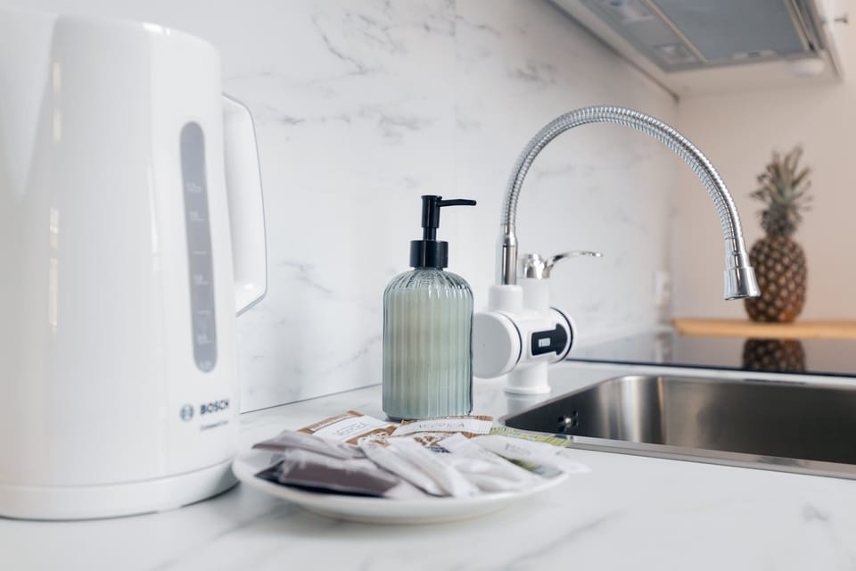 A closer look at the functional kitchen setup, including a kettle, sink, and small storage options.
