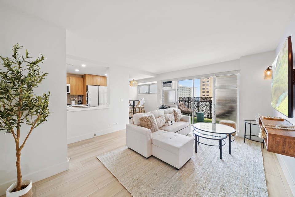 Living room with TV, sofa bed, and sofa sleeper - Enjoy room to stretch out in this newly remodeled Waikiki condo, where modern design, soft lighting, and lanai access make evenings feel relaxed and effortless.