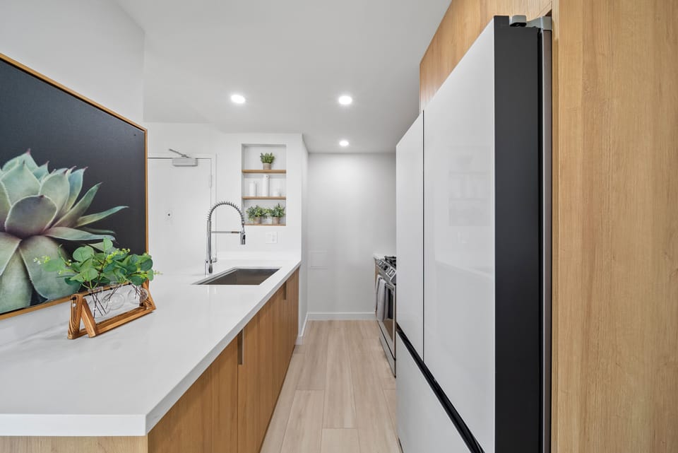 Kitchen with sink and refrigerator - This sleek galley kitchen blends clean lines and bright lighting, offering a functional space to cook, gather, and recharge between Honolulu adventures.