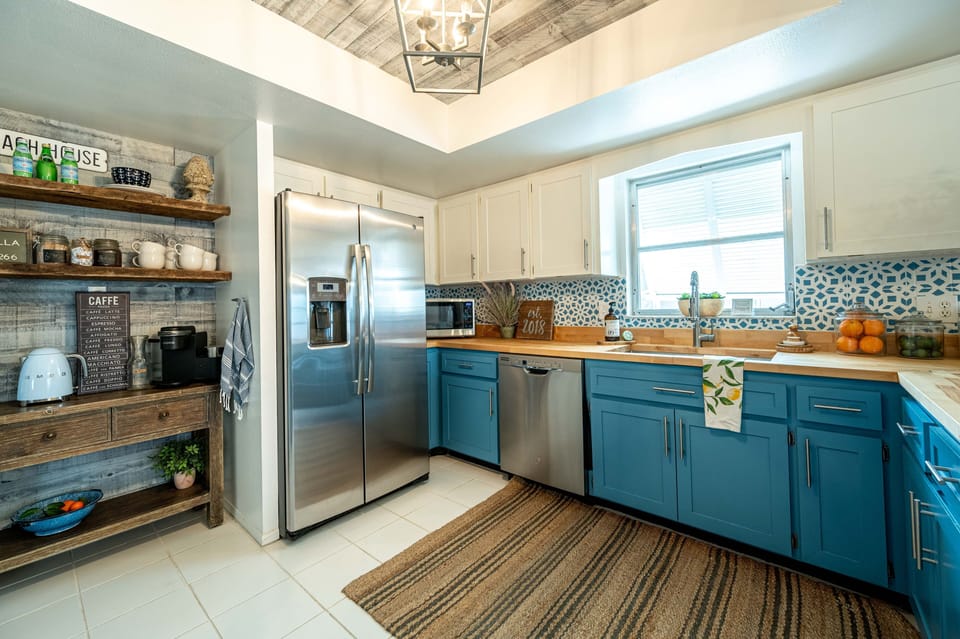 Kitchen alternate view with open shelving, accent lower cabinets, and stainless steel appliances
