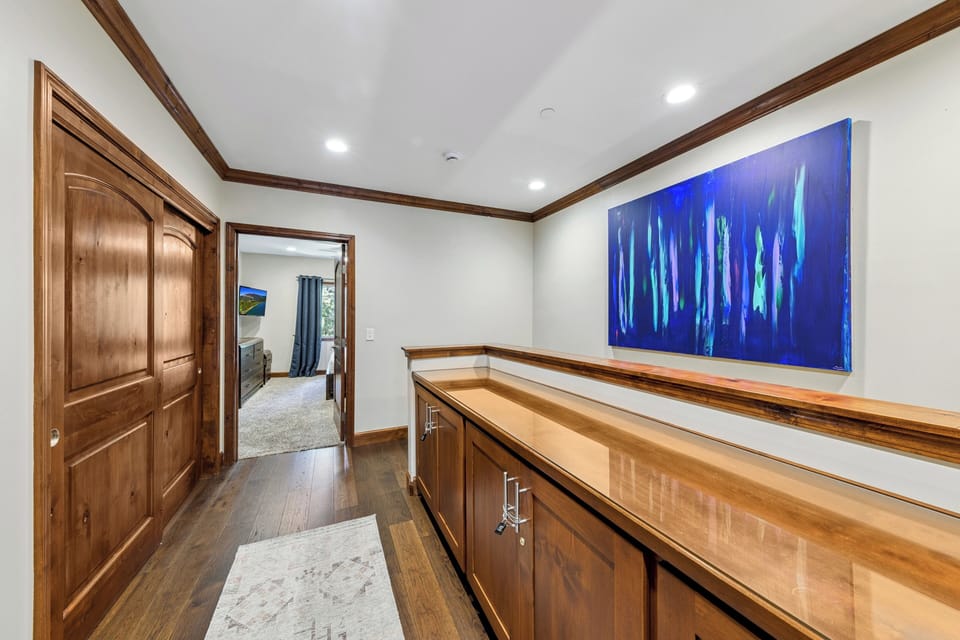 Warm wood tones and thoughtful details create an inviting hallway space with custom cabinetry and striking artwork, leading you seamlessly through your home.