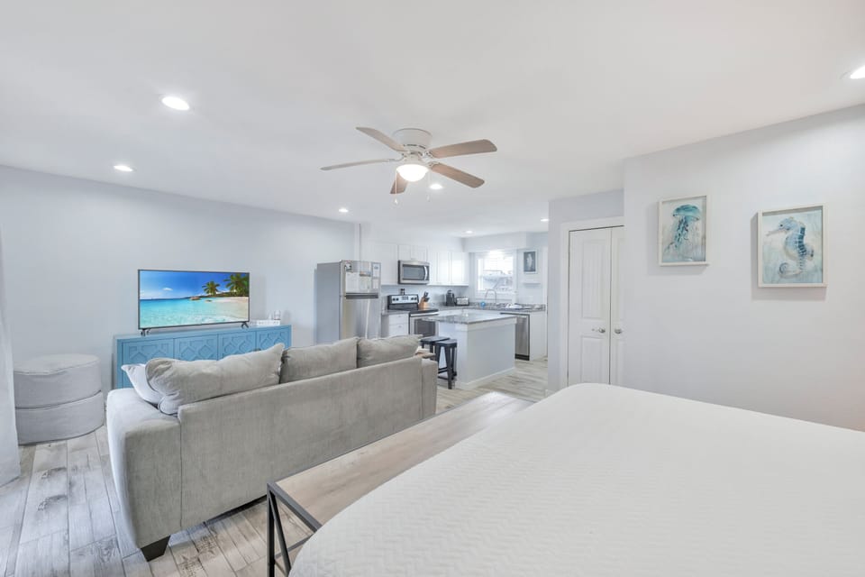 Relax in your bright, open living space featuring a cozy sectional sofa, modern kitchen, and coastal-inspired decor perfect for unwinding.