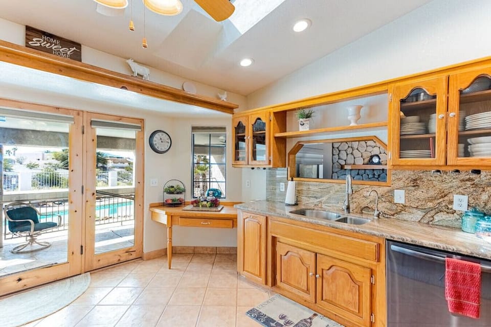 fully equipped kitchen with  the serene views of the pool and backyard oasis through the large glass doors.