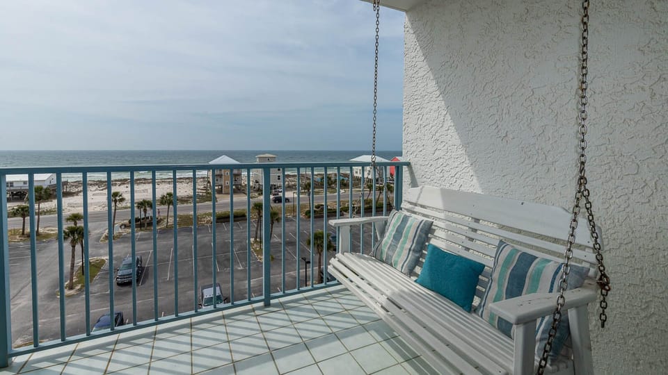 This inviting balcony features a swing with colorful cushions and offers a stunning beach view for relaxing moments