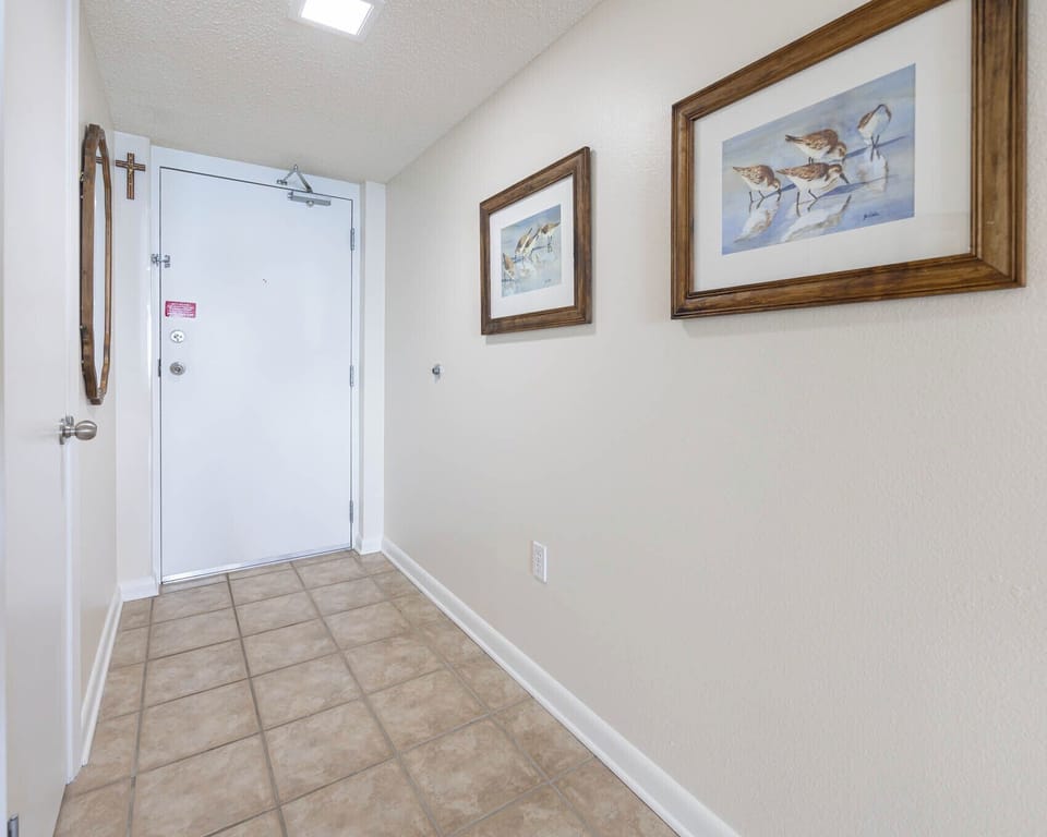 Welcoming entryway features tiled flooring, framed artwork, and a door leading to the main living area