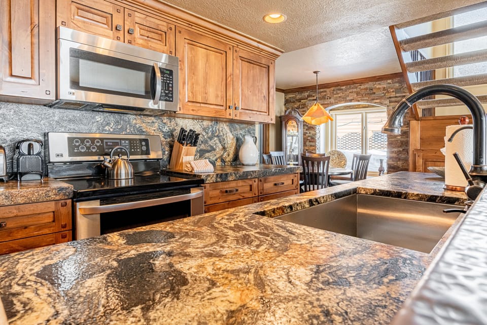 Fully Equipped Kitchen with gorgeous stone countertops, stainless steel appliances, and bar seating for 3