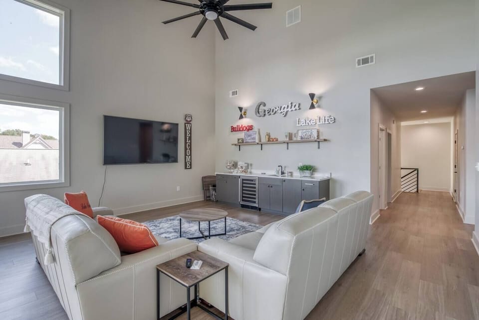 Upstairs living area with WiFi, smart TV, GA Bulldog–themed bar and coffee bar, lake views, ceiling fan, air conditioning, heating, access to the upstairs patio, two sofas, extra blankets, and a full bathroom.