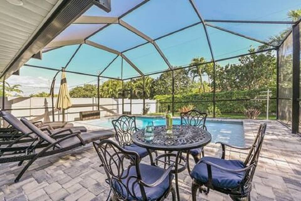 Screened in pool area w/chasers, umbrella, and table.