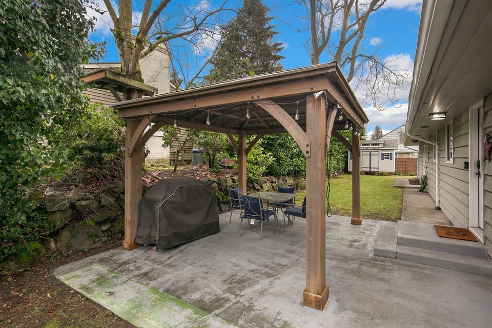 A large private yard with covered gazebo, fenced on three sides with a rock wall along the back