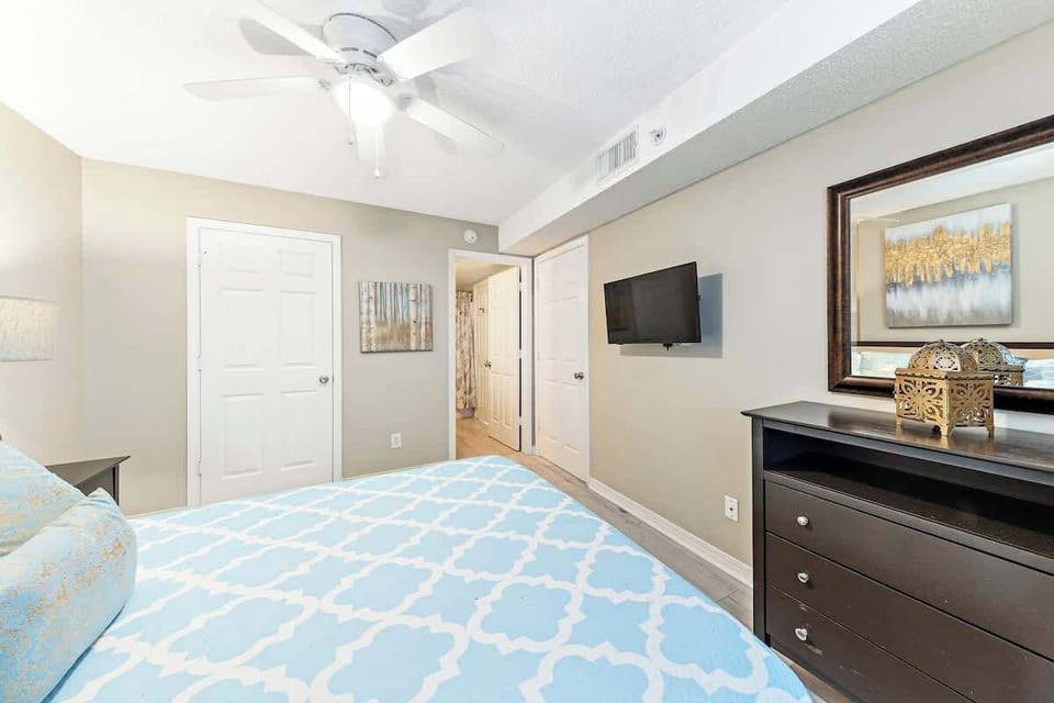 Primary bedroom with smart TV, en suite bathroom, and a calm, coastal feel.