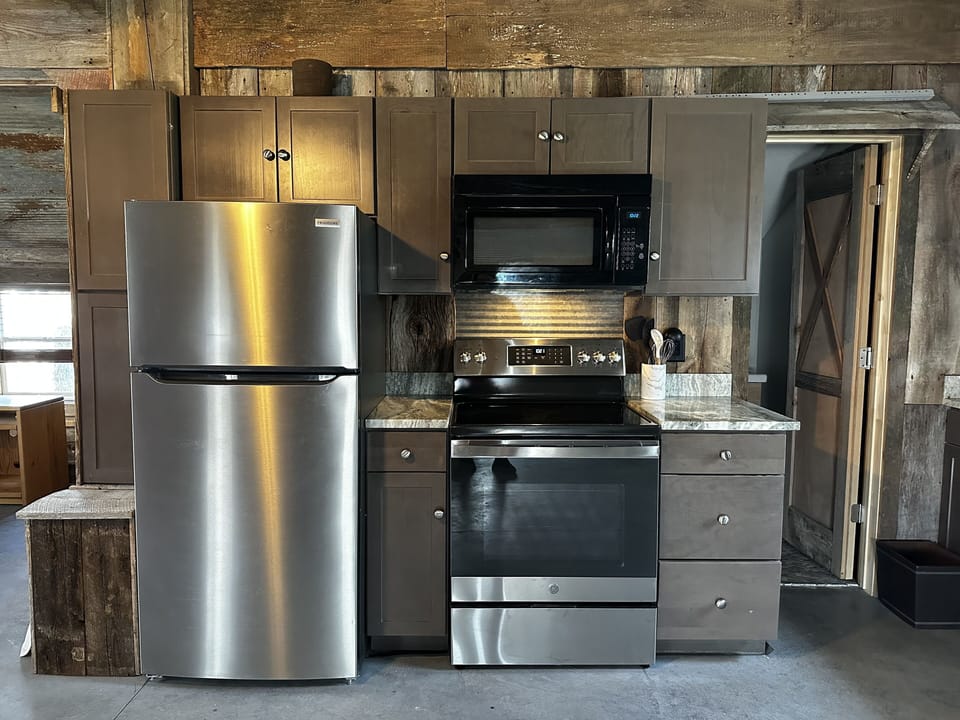 Full kitchen with refrigerator, microwave, oven and single bowl sink. 