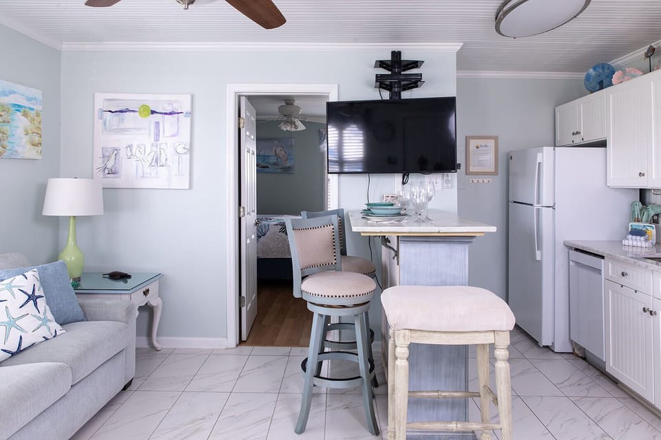 The main room brings everything together in one open, comfortable space. From the sofa to the dining island and kitchen, it’s easy to move through the condo, unpack, and settle in without feeling crowded.