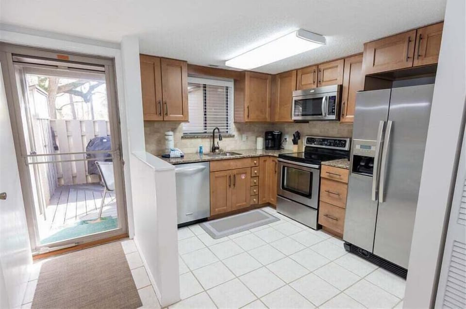 This efficient, well-appointed kitchen is designed for everyday ease, featuring warm wood cabinetry, granite countertops, and a classic tile backsplash.