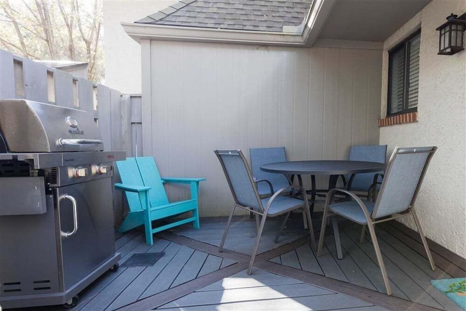 The wood deck is furnished with a grill, dining table, and chairs, ideal for relaxed meals or morning coffee in the shade.