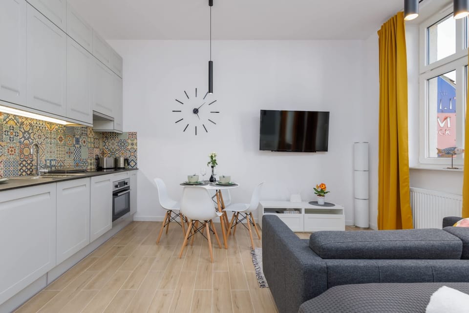 A view of the kitchen and dining area with stylish decor and a wall-mounted TV.
