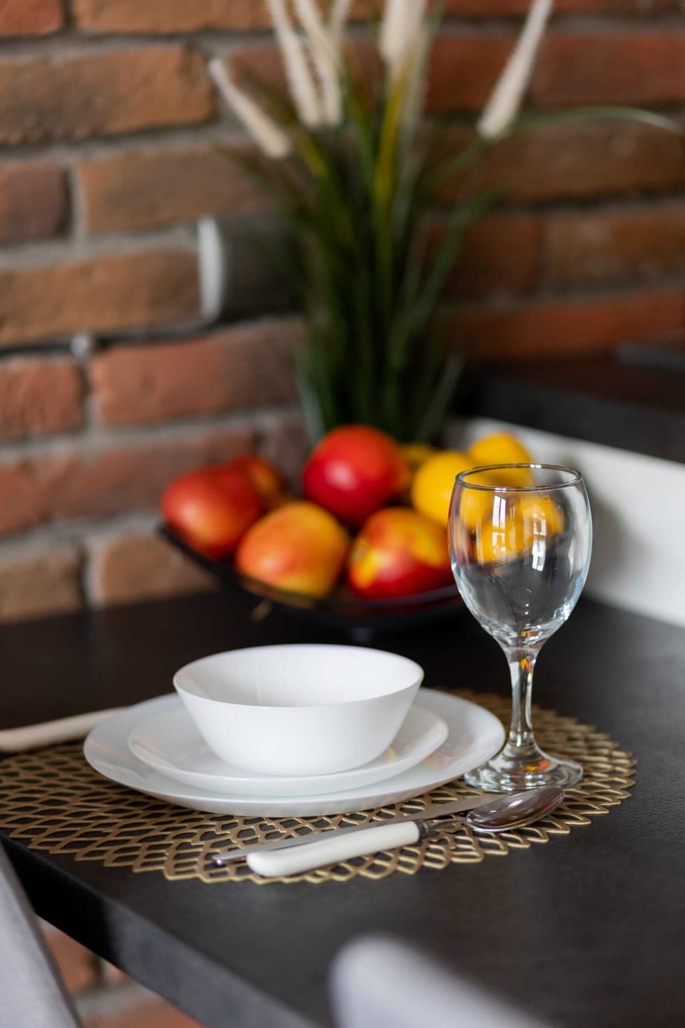 A close-up of a round black table with a vibrant red pillow on the sofa in the background. The composition adds warmth and style to the room.