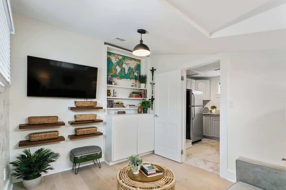 Upstairs lounge with large TV, cozy seating, and built-ins stocked with books and storage baskets. A comfortable spot to unwind, work, or stream after exploring the Quarter.