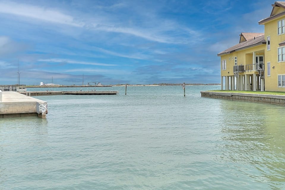 Waterfront property nestled along pristine turquoise waters with private marina access and charming yellow coastal architecture.