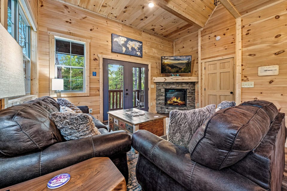 Living room with doors leading to the back deck & cozy electric fireplace.
