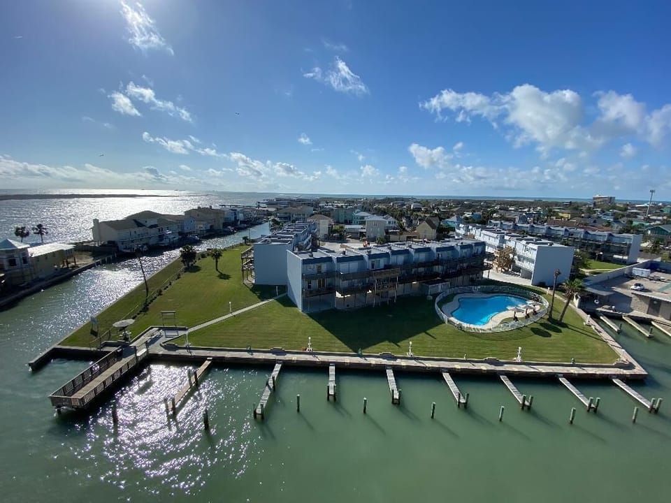 Waterfront property with marina docks, swimming pool, and expansive green space overlooking pristine waters and residential coastline.