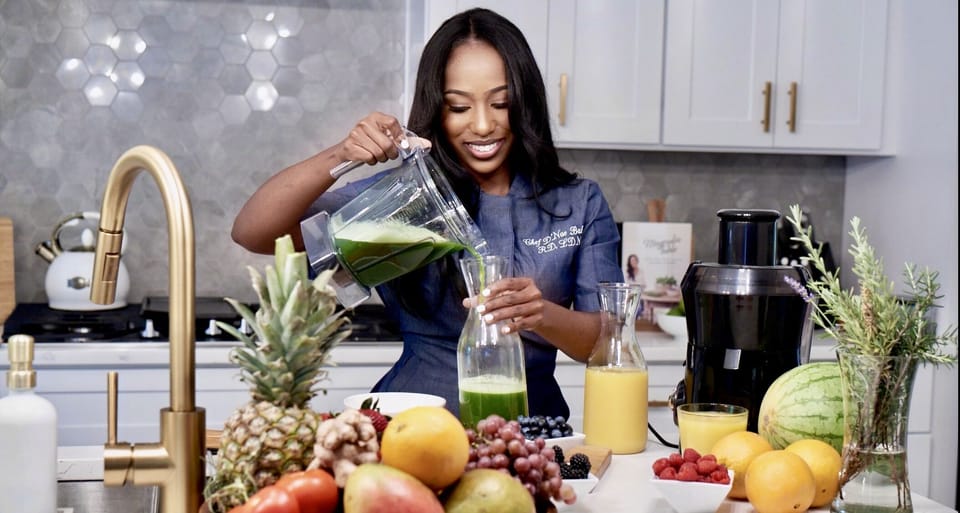 Fresh juice prep in a bright kitchen setting w/ colorful fruits on display
