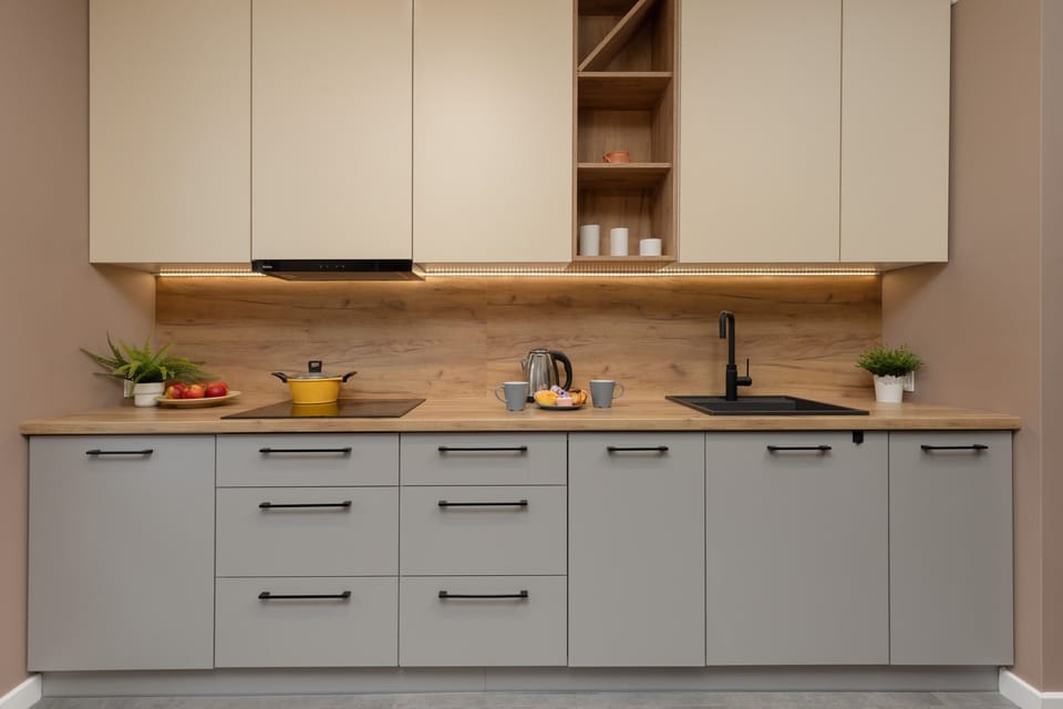 A bright and functional kitchen with gray cabinets, wooden shelving, and decorative accents.
