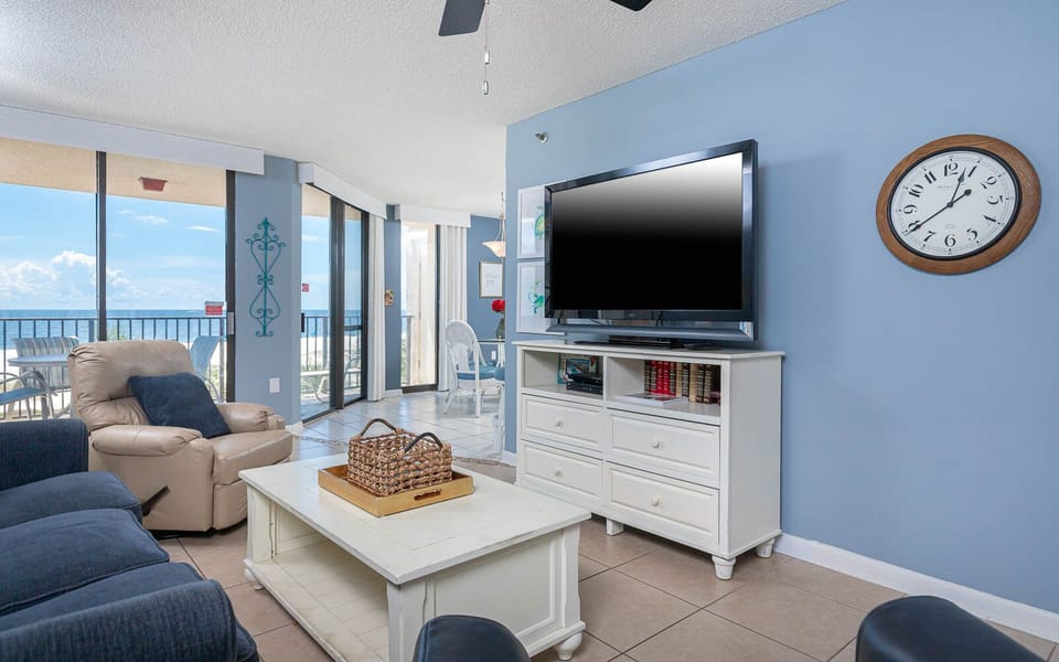 Relax in the inviting living area featuring a large TV, cozy sofa with queen sleeper, and a beachfront view