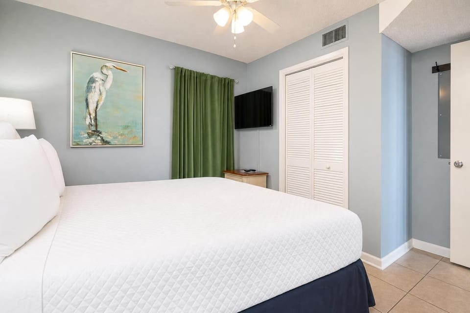 Relax in the serene king suite featuring a plush bed, a TV, and calming decor highlighted by soft green curtains