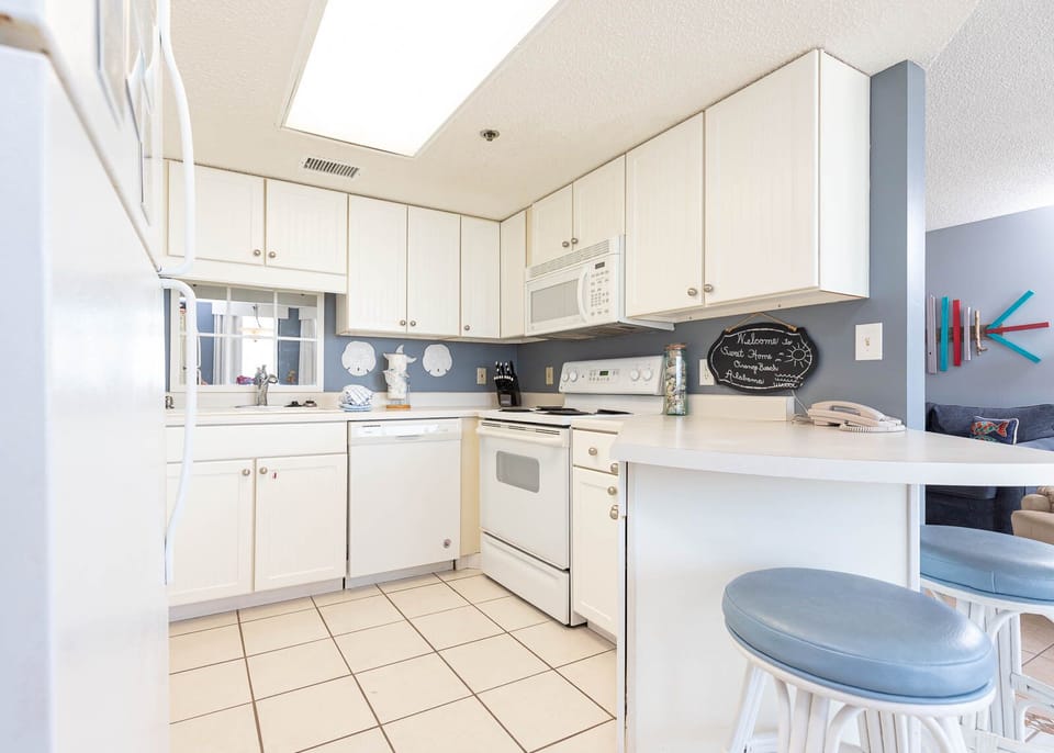 Prepare meals in the kitchen featuring white cabinetry, white appliances, and a convenient breakfast bar