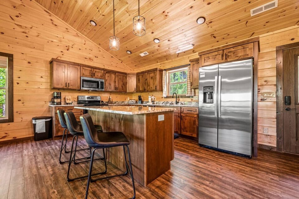 Fully-equipped kitchen with stainless steel appliances and additional bar seating at the island.
