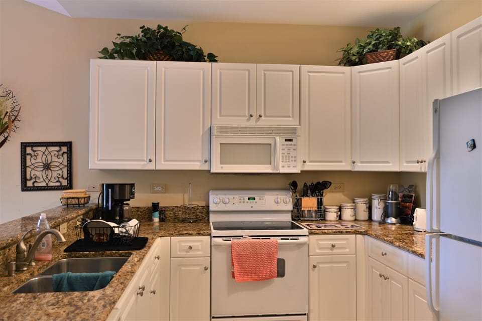 Modern kitchen with white cabinets, granite & efficient appliance layout.