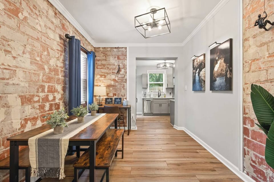 Dining room with desk area boasts exposed brick walls and flows into full kitchen and living areas.