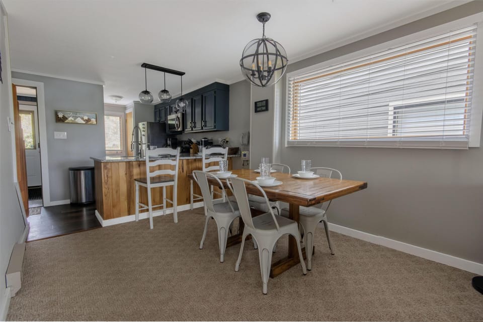 The dining area features seating for six people (two chairs not pictured), plus additional seating for two at the breakfast bar with granite countertops.
