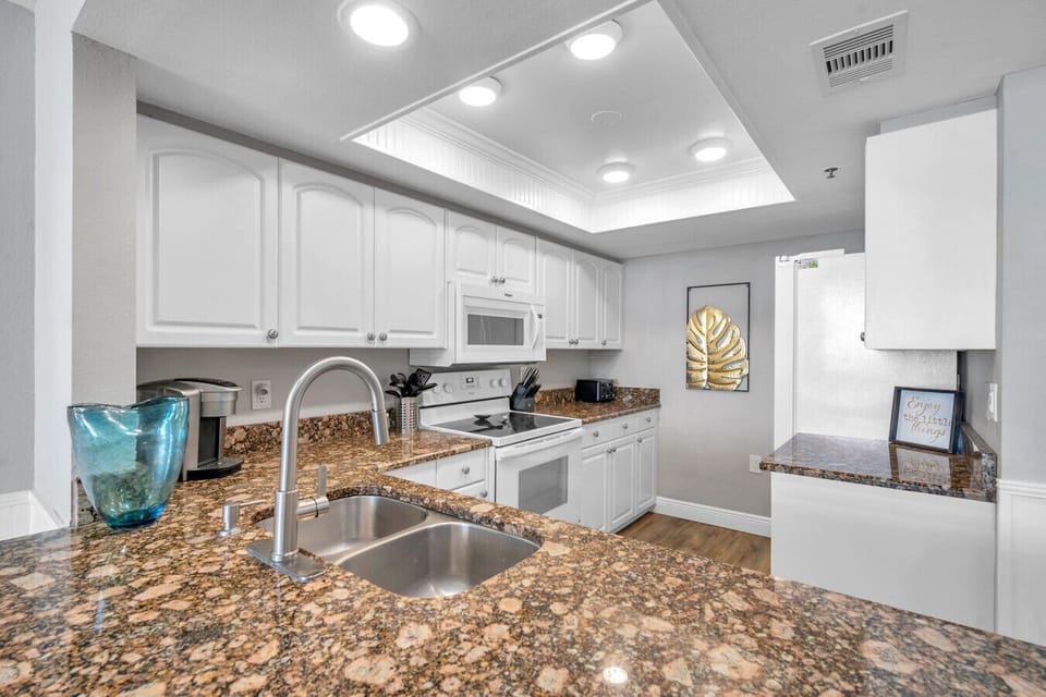 Kitchen close-up w/ granite counters, white cabinetry, & plenty of prep space.