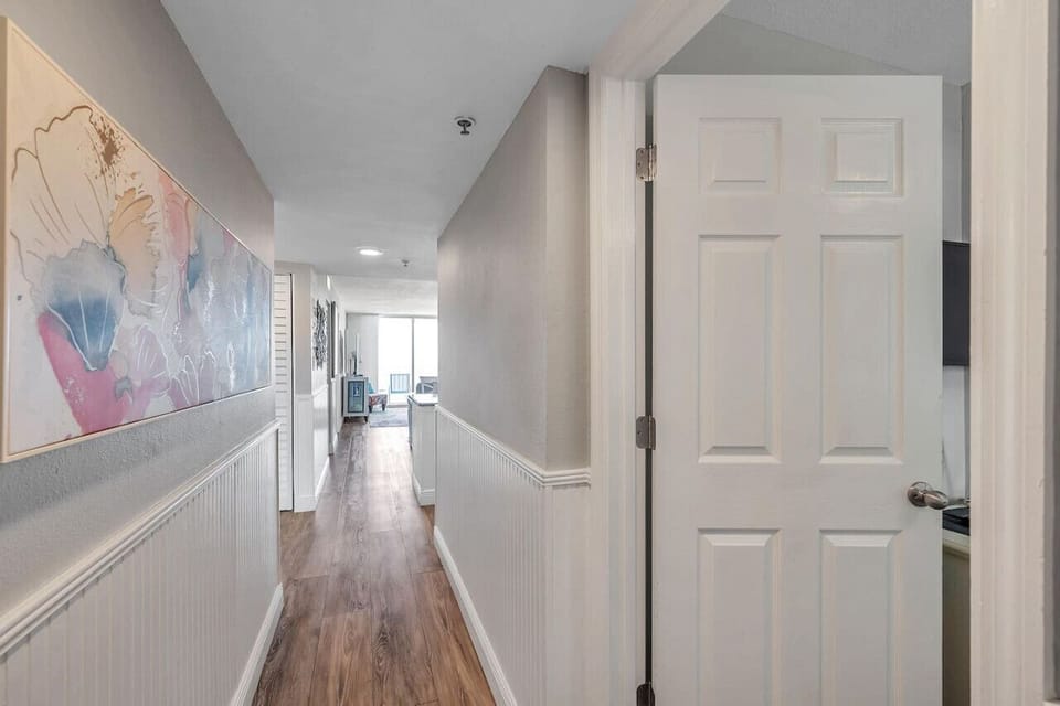 Bright hallway w/ coastal artwork, leading smoothly through the home.