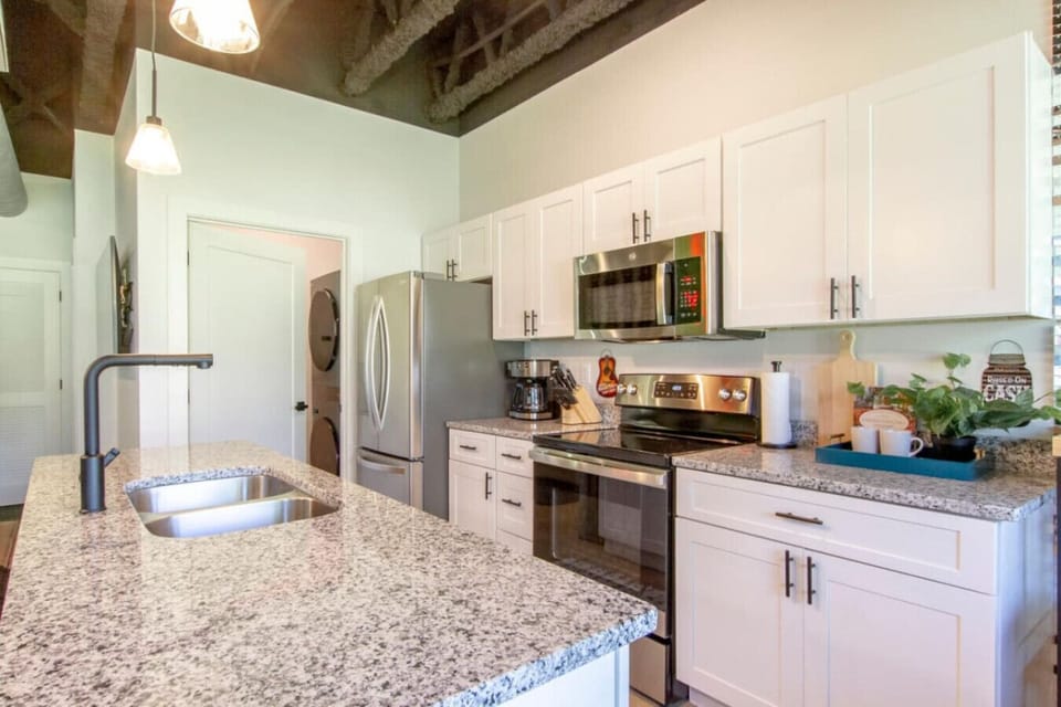 Fully equipped kitchen with white cabinets, stainless microwave, and granite counters ready for cooking