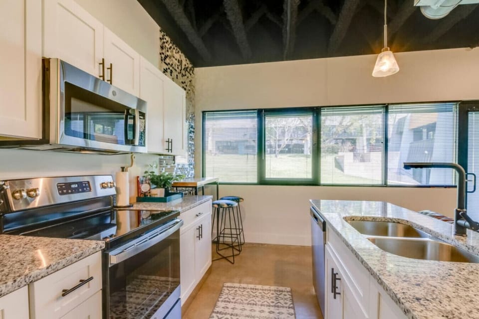 Sleek kitchen with dark cabinets, stainless steel appliances, granite counters, and a breakfast bar