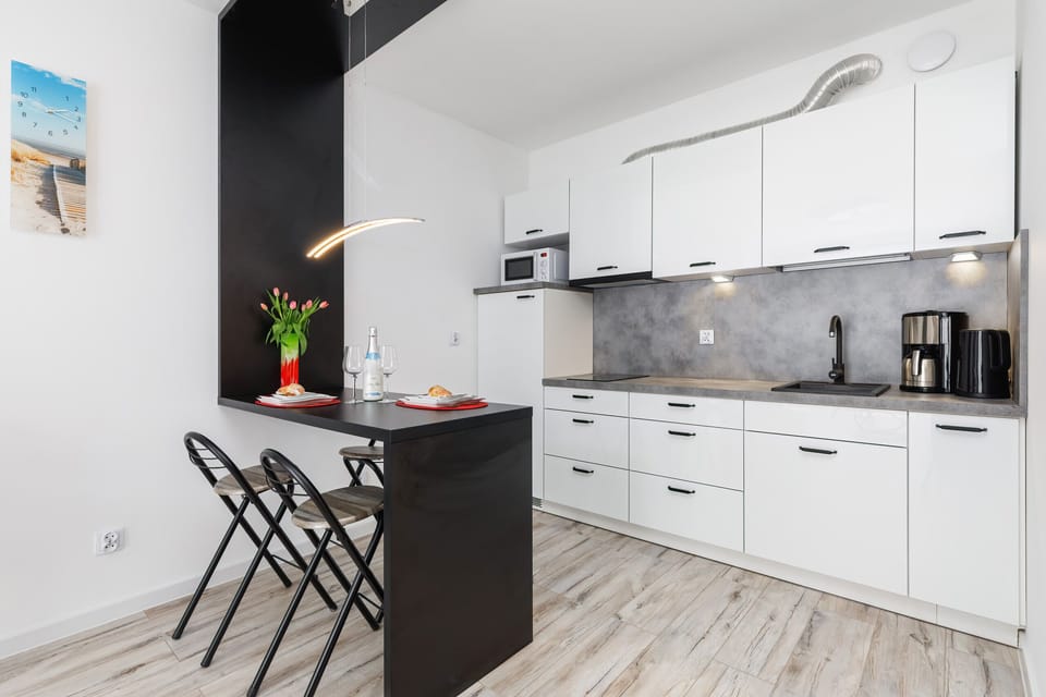 Contemporary kitchen with sleek white cabinets, a breakfast bar, and modern appliances for cooking convenience.
