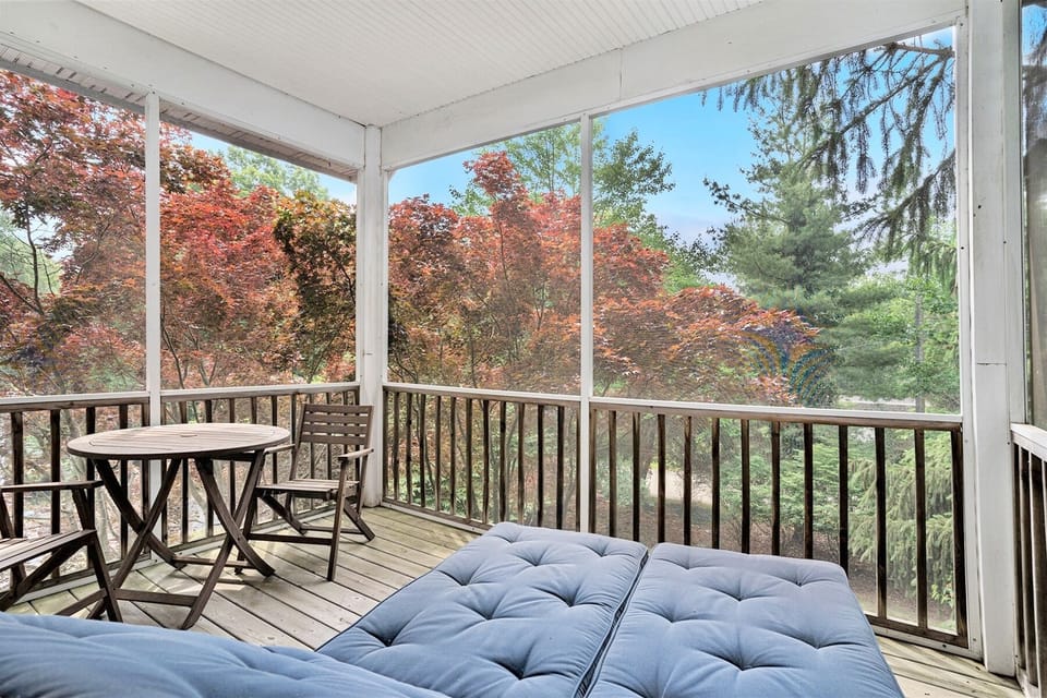 Screen porch off the guest room has two cushioned loungers and a cafe table