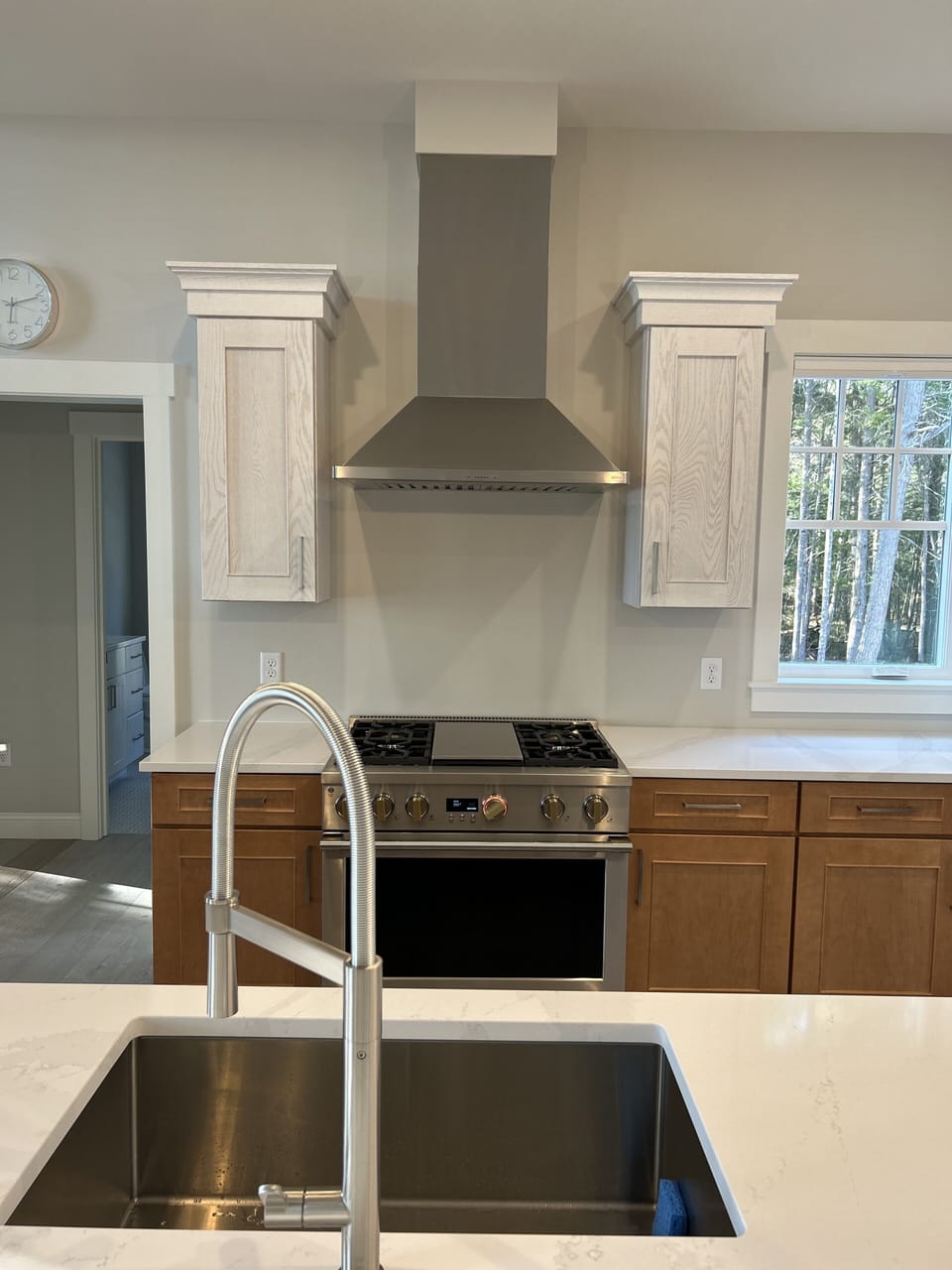 Kitchen has island sink and full venting system over the stove