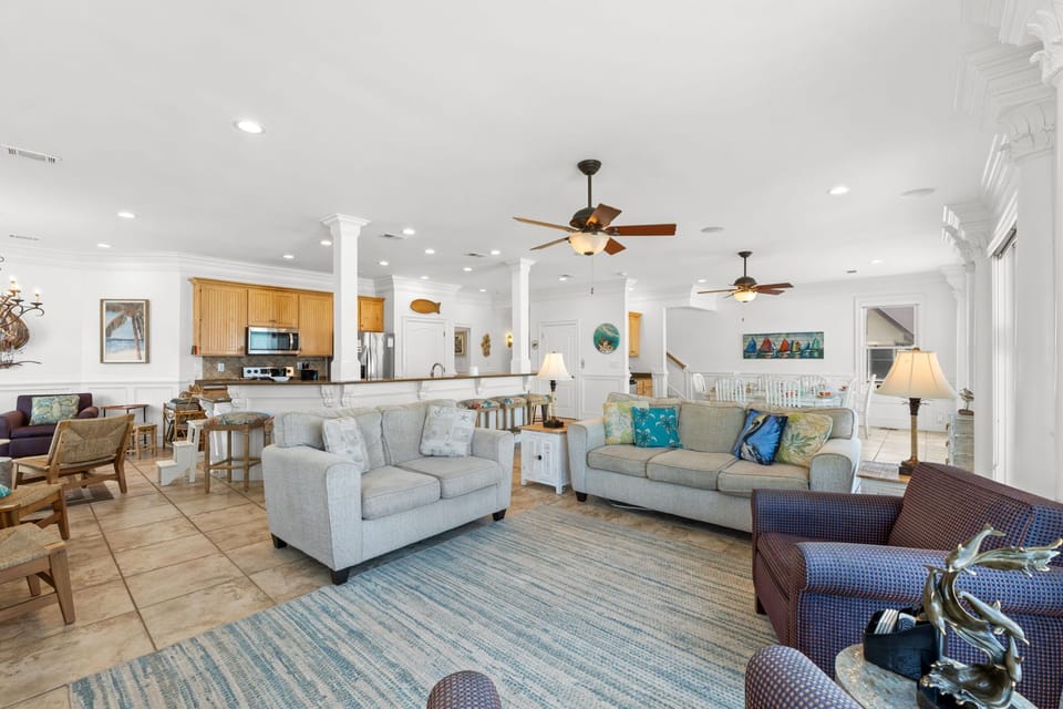 Relax in this bright, open living space where coastal charm meets comfort. Sink into plush sofas, enjoy the breeze from ceiling fans, and gather with loved ones in a home designed for memorable vacation moments.