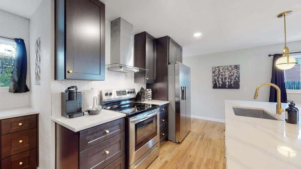 A beautifully designed kitchen with sleek dark cabinetry, stainless steel appliances, and a spacious island, offering both functionality and style.