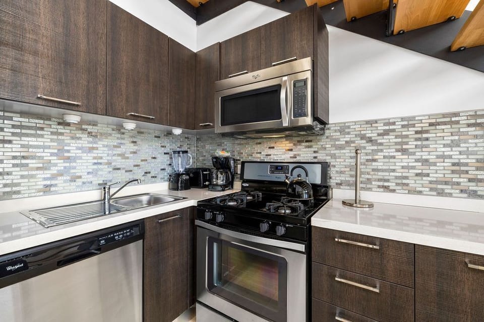 Modern kitchen complete with all necessary appliances ie. stove, coffee maker, blender, microwave and fridge.