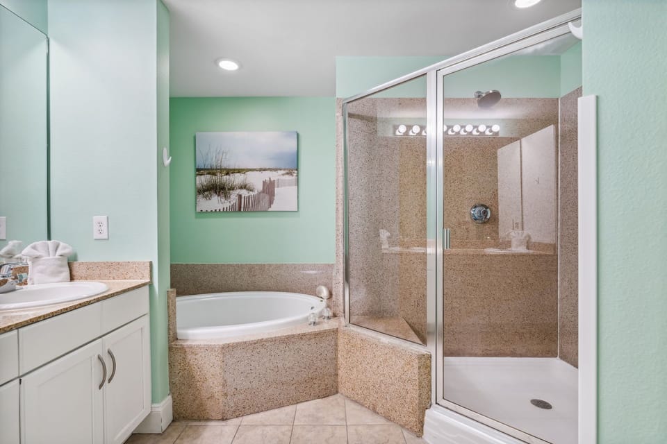 Relax in the spacious bathroom featuring a separate shower and soaking tub with a coastal-themed decor.