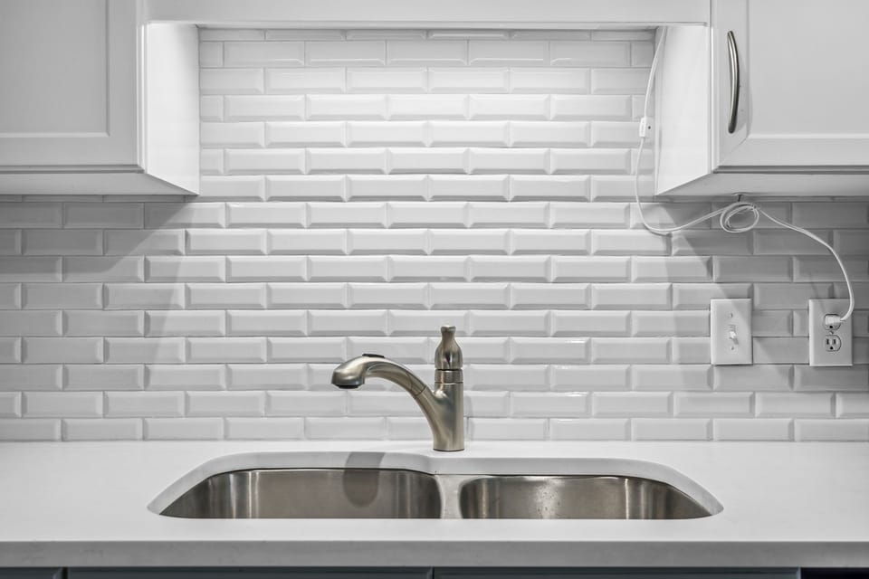 modern kitchen sink with stainless steel faucet and white subway tile backsplash