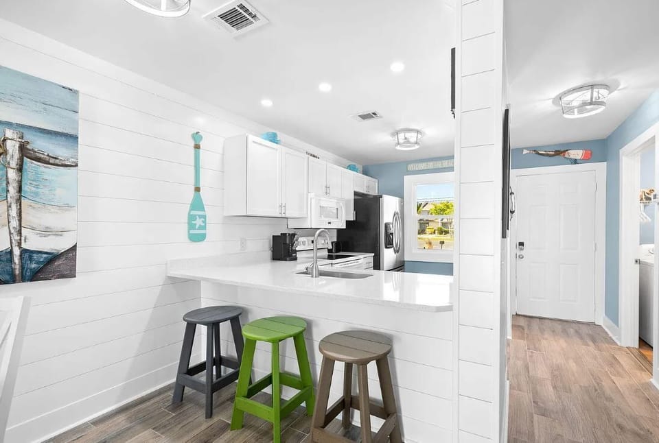 Modern kitchen with white cabinetry and a breakfast bar featuring colorful stools.