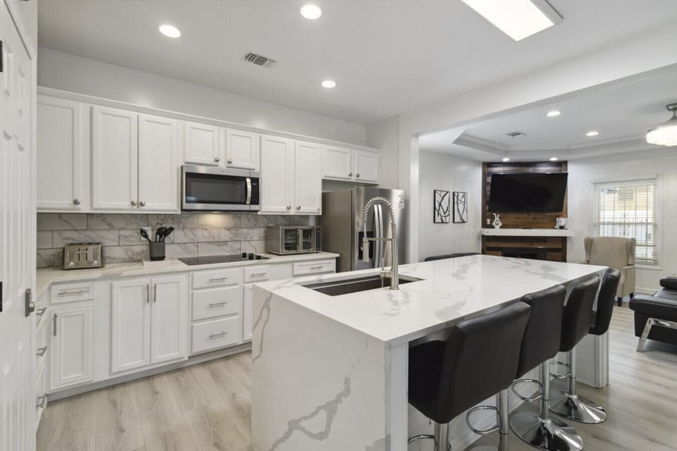Step into a kitchen where modern design meets everyday functionality—a sleek culinary haven that’s as stylish as it is practical. Anchored by a chic bar counter with high chairs, this space invites casual conversations over coffee or cocktails. The minima