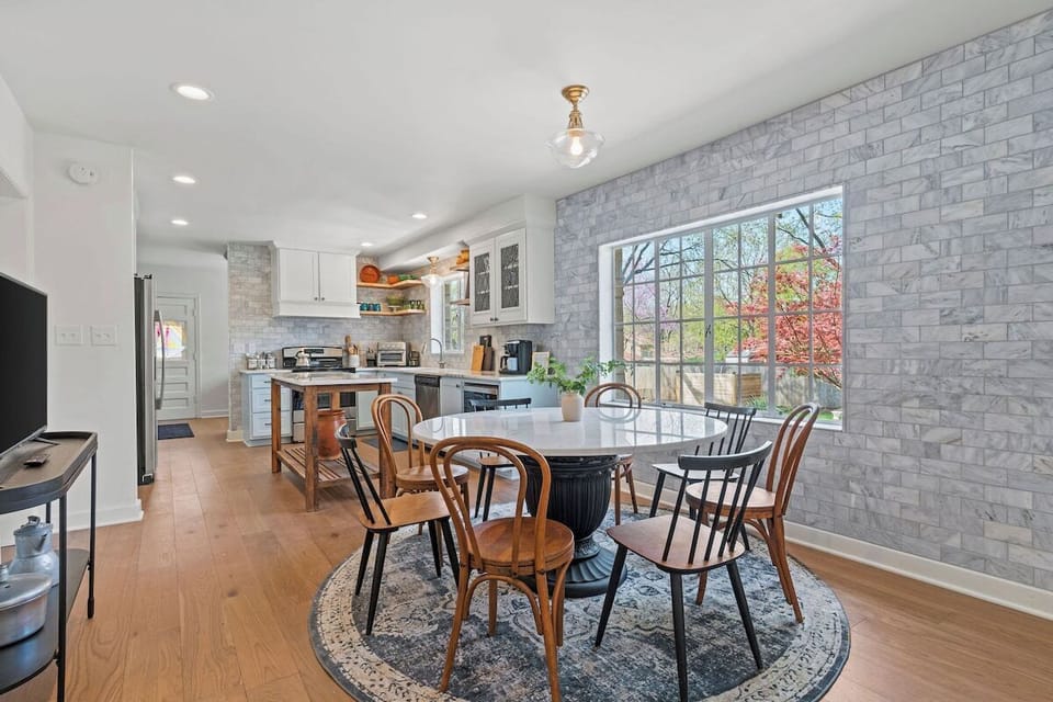 Spacious dining area with a round table, stylish seating, and natural light, seamlessly connected to the full kitchen. A Smart TV nearby makes it easy to enjoy meals, games, or casual gatherings.