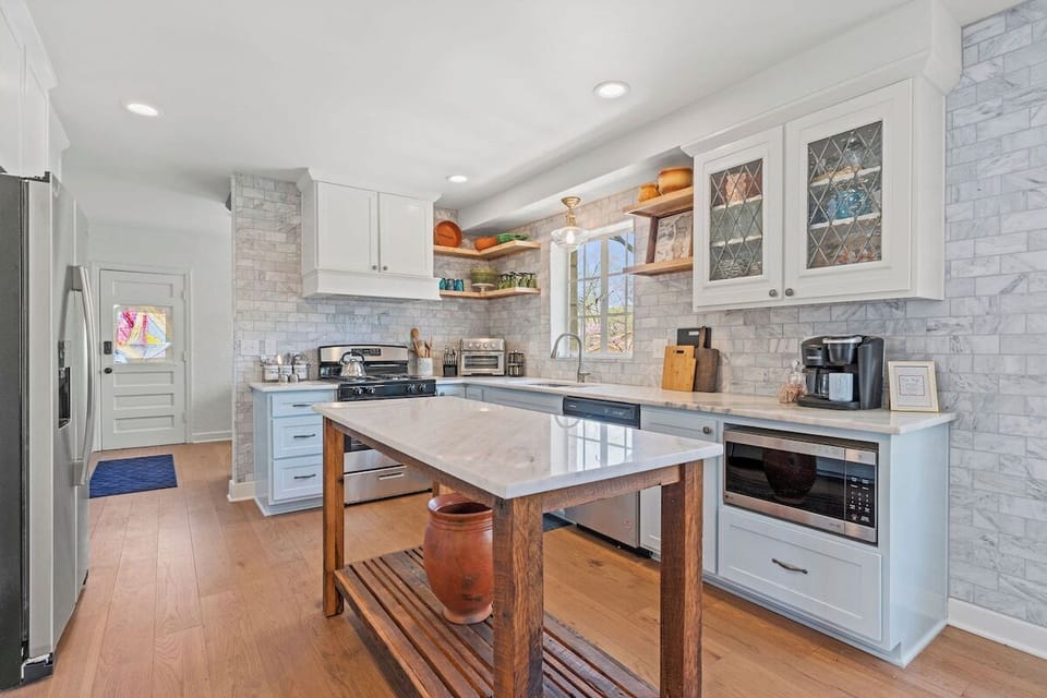 Bright, fully equipped kitchen with marble countertops, gas range, stainless steel appliances, and a spacious prep island—perfect for cooking meals at home during your Kansas City stay.